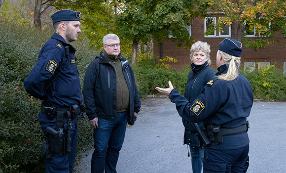 Foto på två poliser som pratar med en man och en kvinna.